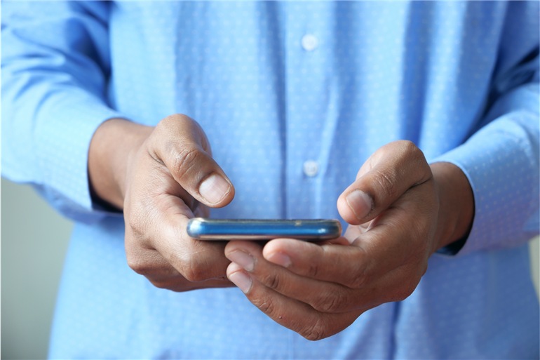 homem segurando celular para enviar sms